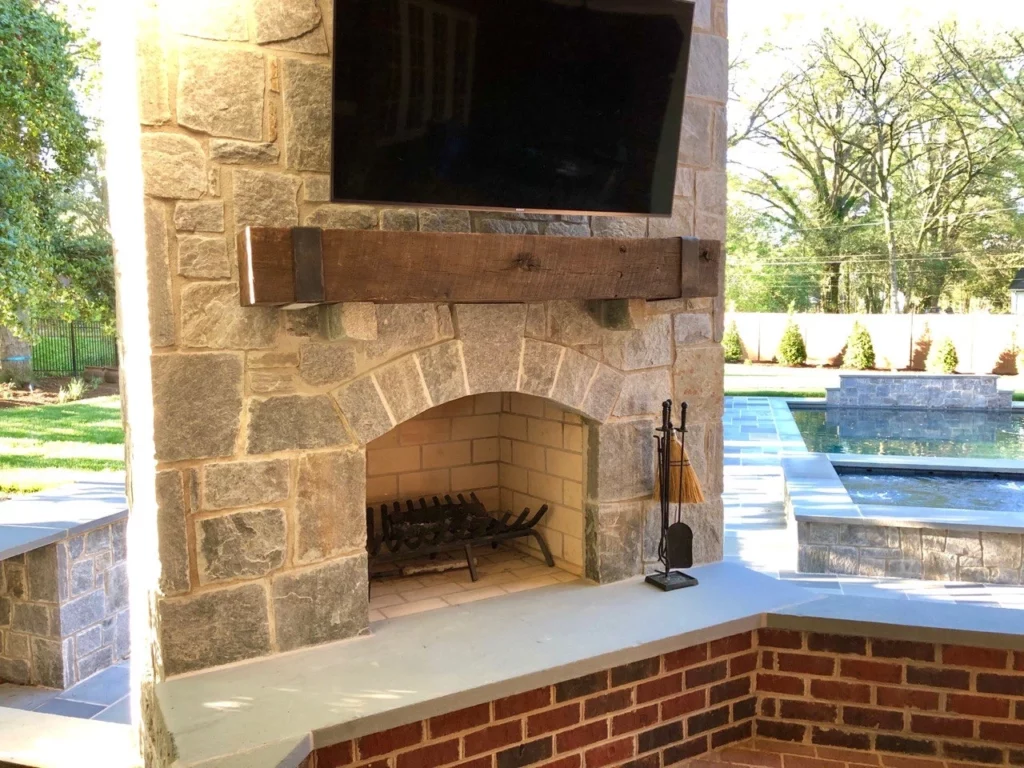 An outdoor fireplace with a tv mounted above it.