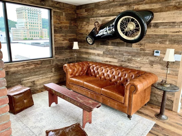 A living room with a leather couch and a motorcycle on the wall.