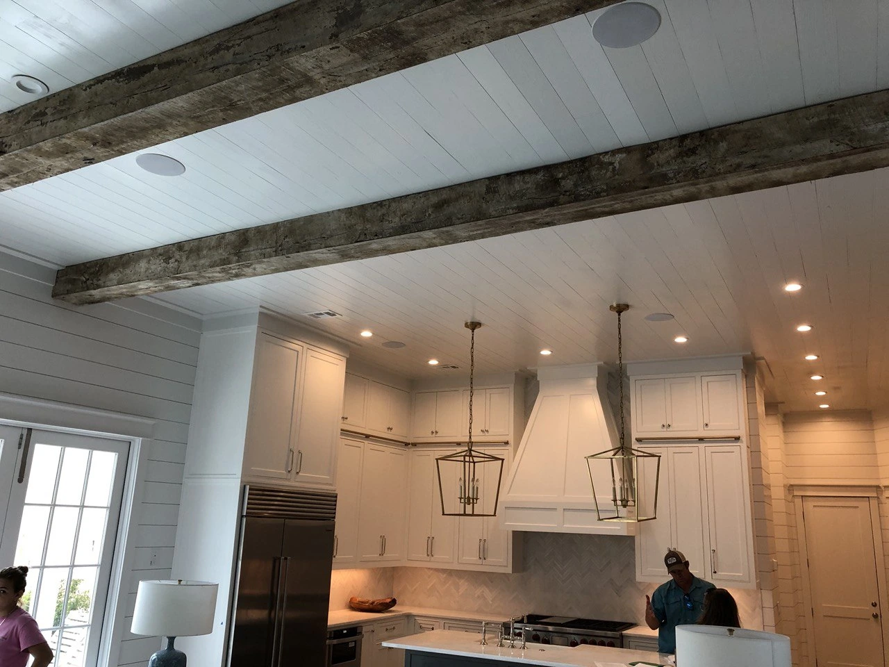 A white kitchen with wood beams in the ceiling.